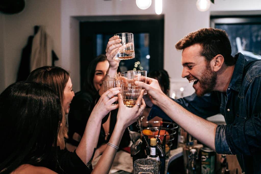 Group of friends raising glasses in a celebratory toast at a lively indoor restaurant.