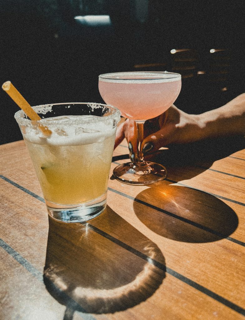 Two refreshing cocktails on a wooden table, perfect for cooling off in Grand Cayman.